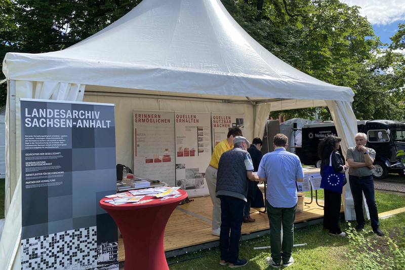 Informationszelt mit Aufstellern des Landesarchivs, davor ein Stehtisch mit Informationsmaterialien sowie mehreren Personen im Gespräch